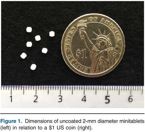 Photo which shows pharmaceutical minitablets in comparison to a 1 cent US coin