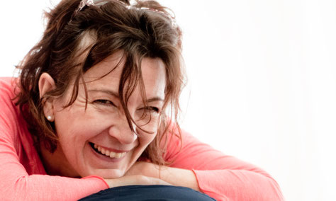 Birgit Schnopfhagen, Physiotherapeutin, lächelt herzlich und lehnt entspannt auf ihren Armen.
