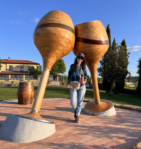 monumento in legno a forma di due calici di vino sotto al quale ci sono io