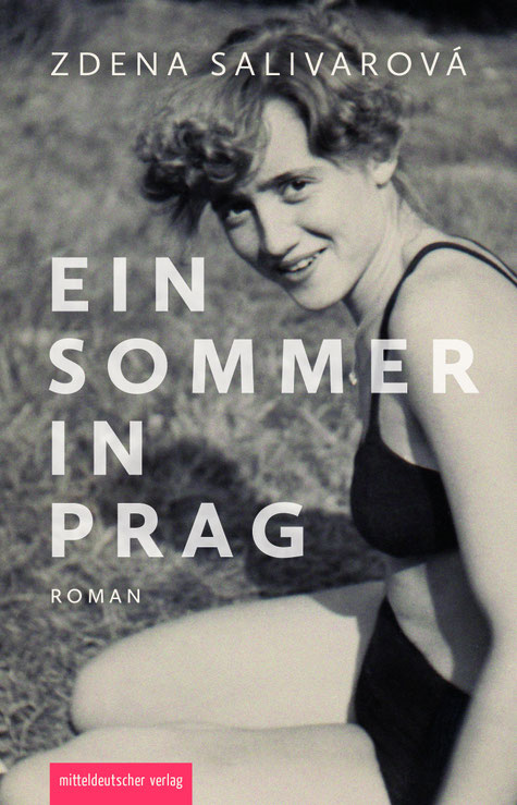 Das Cover von "Ein Sommer in Prag" zeigt eine Frau in Badekleidung, die im Gras sitzt und in die Kamera lächelt.