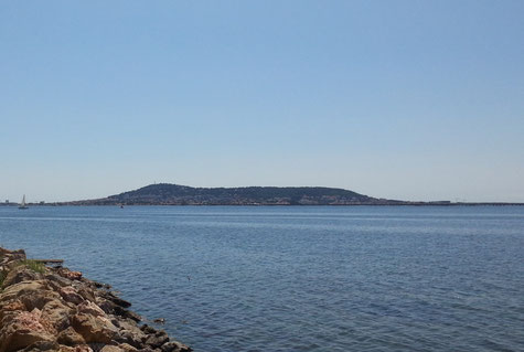 Vue du mont Saint-Clair depuis une jetée en pierres du pot de Bouzigues, l'étang de Thau tout juste ridé est séparé du ciel lui aussi tout bleu, par la masse trapue et noire du mont.