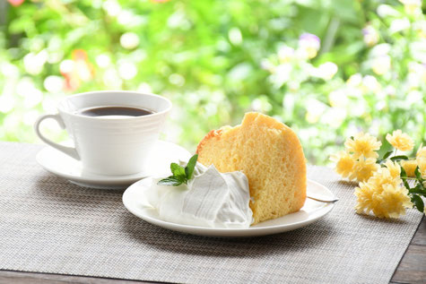 生クリームが添えられたシフォンケーキのお皿とコーヒーの入ったカップ&ソーサ。