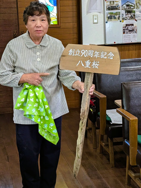 2026年6月7日（日）森牧師が兼務する十文字平和教会でのひとこま。礼拝後、一年前に植樹した八重桜の脇に立てる案内版がやすこさんのご奉仕で出来ましたよ、との報告をして下さっているのは君江さんです。立派な立て看板が出来ました。嬉しいことです。
