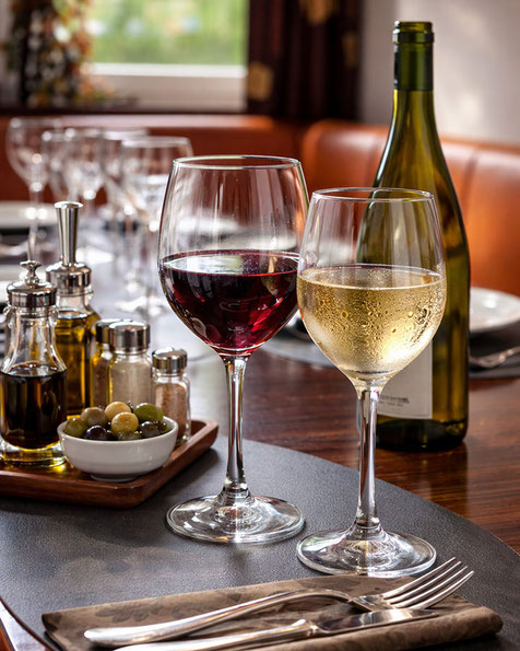 Zwei Weingläser mit Rotwein und Weißwein im gemütlichen Ambiente des italienischen Restaurants Gusto Italiano Kirchbichl, Tirol.