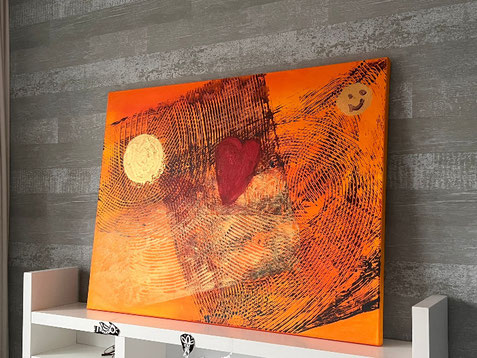 Oranjeschilderij 60 bij 80 cm doek, met daarop aangebrachte speelsegrafische structuren en een gouden zon en een warmrood hart en een smiley