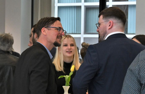 Gespräche unter mehreren Gästen an Stehtischen.