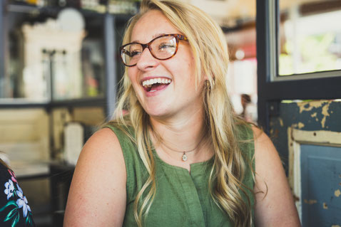 femme-blonde-a-lunettes-qui-regarde-sur-le-cote-et-qui-rit