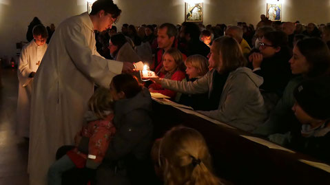 Das Friedenslicht wird an die Messbesucher weitergegeben, Foto von der Kindermette am 24.Dezember 2024.