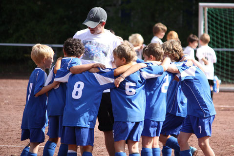 Niños jugando al fútbol reunidos con el entrenador