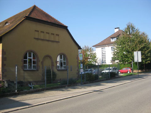 Sicht auf die Turnhalle (links gelbes Gebäude) und Einfahrt vom Parkplatz