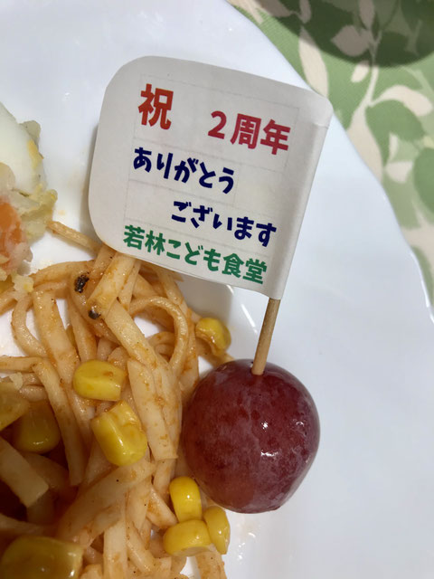 ☆お料理のプレートの真ん中にブドウに刺した楊枝の旗「祝 2周年 ありがとうございます 若林こども食堂」。