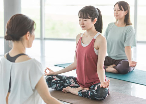 セミパーソナルのレッスンで、講師と生徒2名が蓮華座（パドマーサナ ）のポーズをしています。