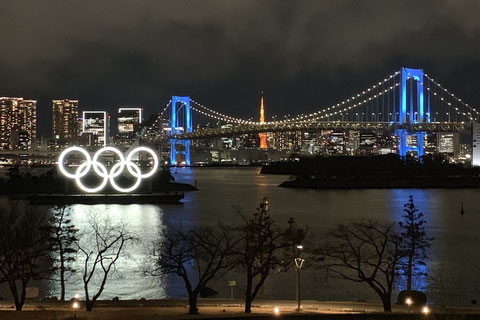 東京タワーと夜景を背景にしたお台場海浜公園の五輪シンボル