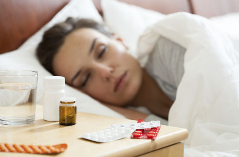 Mujer en la cama con fiebre, tomando pastillas