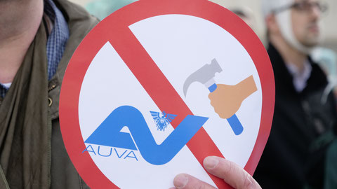 Demonstrant hält AUVA-Button