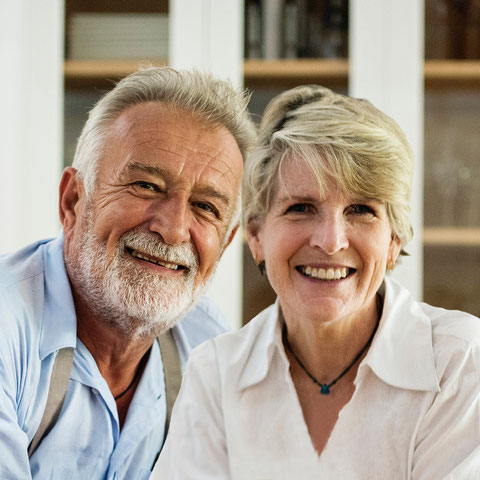 Ein älteres Paar lächelt Kopf an Kopf in die Kamera