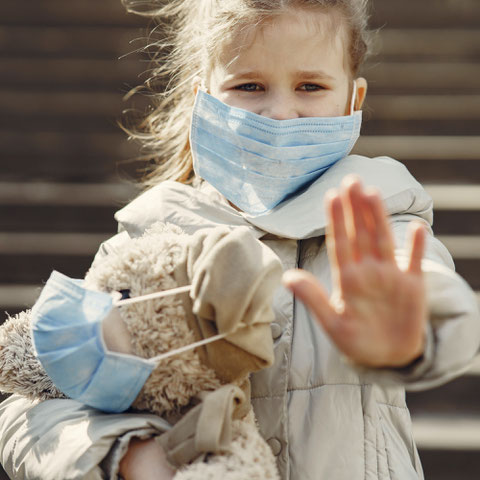 Kleinkind mit Maske hält ein Kuscheltier mit Maske