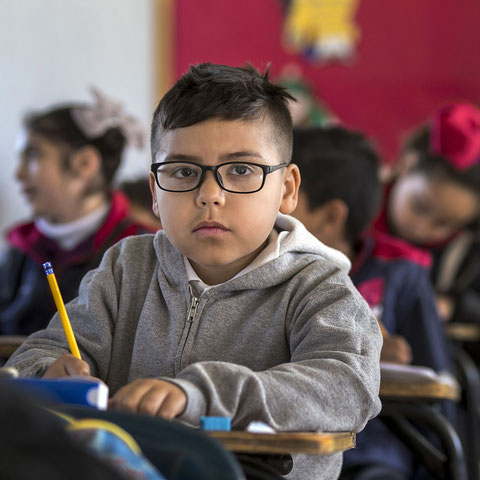 Ein Junge mit dunkler Hautfarbe sitzt in einer Klasse