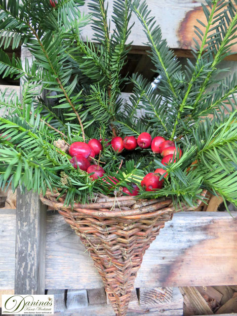 Herbstdeko für draussen: Eibenzweige und Zierapfel Kranz in Weidenkorb