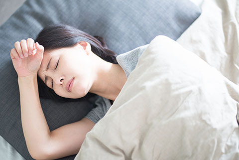 しんどそうに眠っている女性のイメージ