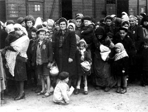 Selektierte Frauen und Kinder, vermutlich aus einem der ungarischen Transporte, auf der Rampe kurz vor dem Weg in die Gaskammern. Im Hintergrund die Waggons der Deutschen Reichsbahn.