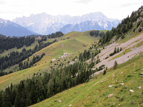 In der Bildmitte die Almhütten der Feistritzer Alm, im Hintergrund die mächtigen Nordwände der Julischen Alpen