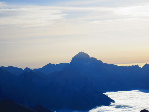 Der König der Julier, der Triglav zeigt sich in voller Pracht im Morgenlicht, links neben dem Gipfelaufbau das blinkende Blechdach der Hütte auf der Kredarica