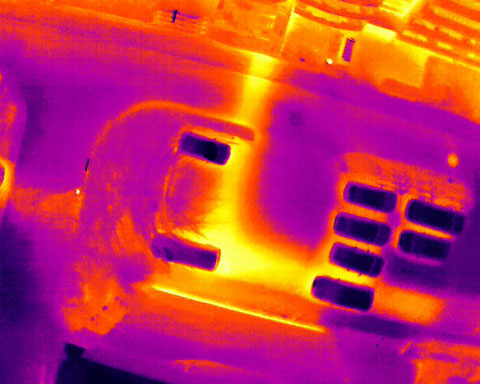 Thermografische Drohnenaufnahme einer Fernwärmeleitung mit sichtbaren Wärmeverlusten entlang der Trasse.