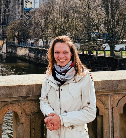 Bild von Valeria Lücke, Geschäftsführerin, vor einer Brücke stehend, lächelnd.