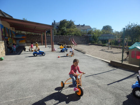 Dans la cour, on peut jouer avec les tracteurs à pédales, les trottinettes, les échasses...