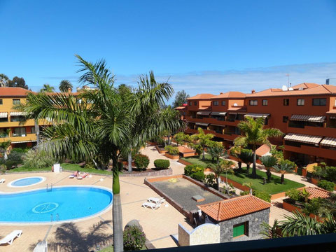 Blick von der Terrasse auf den Gemeinschaftspool und den subtropischen Garten der Wohnanlage.