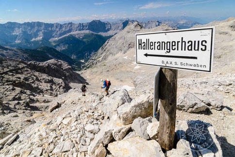 zwei Wanderer im alpinen Gelände mit Wegweiser zum Hallerangerhaus