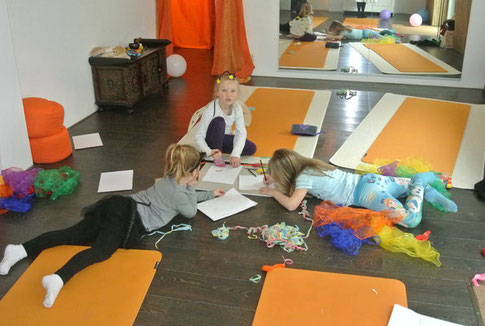 Zum Ende der Kinderyoga Stunde malen und basteln drei Kinder