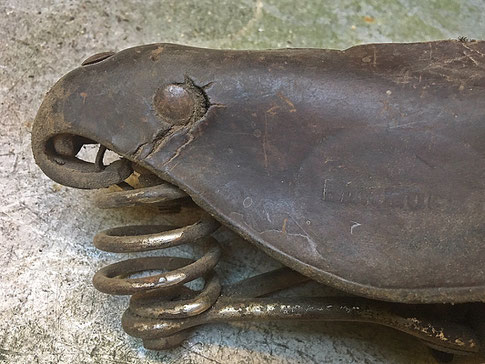 Verhärtung und Risse im Leder an einer seitlichen Niete der Sattelnase bei einem historischen Fahrradsattel mit Lederdecke