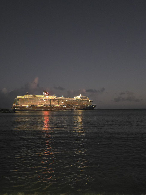 Beleuchtetes Mein Schiff Kreuzfahrtschiff bei Nacht am Hafen mit Spiegelung im Wasser