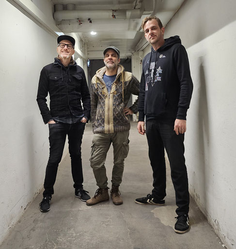 Die drei Bandmitglieder in einem Kellergang.