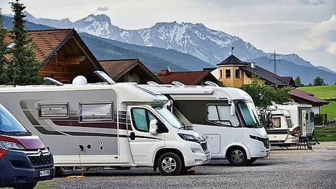 Mehrere Wohnmobile vor Bergkulisse. Camping-Urlaub boomt in der Corona-Zeit. Gut geschützt mit einer Camping-Reiseversicherung und CDW-Versicherung der ERGO.