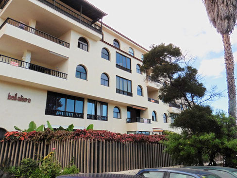 Wohnhaus mit 5 Etagen in einem hellem Farbton gehalten und einer ruhigen Strasse davor.