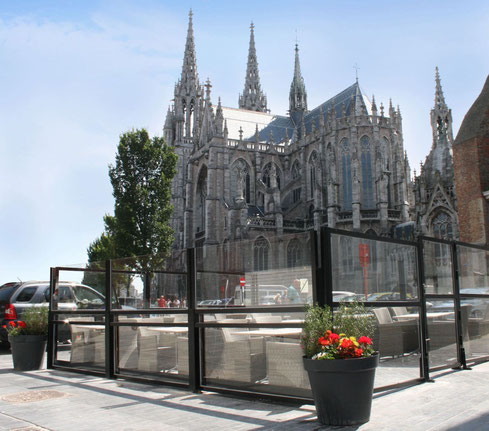 Restaurantterrasse mit Glas Windschutzsystem in historischer Kulisse.