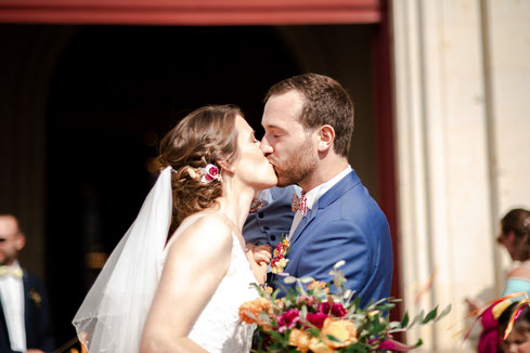 Baiser des mariés à la sortie d’église pour un mariage coloré décoré par My Daydream Wedding près de Nantes