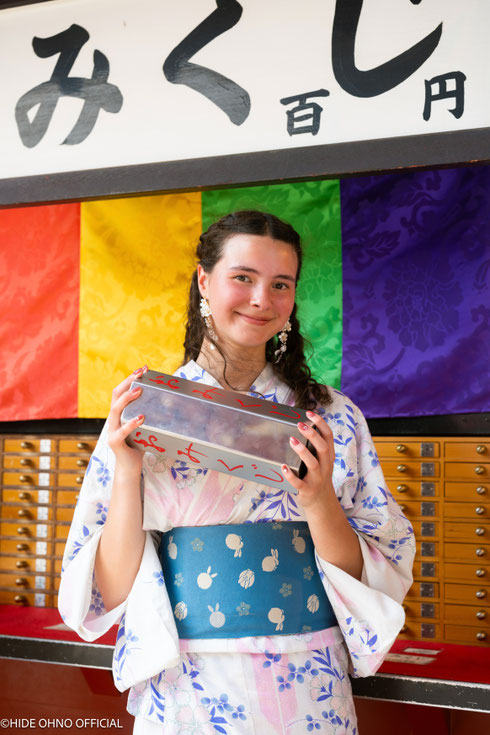Woman in yukata drawing omikuji fortune slip at Sensoji Temple in Asakusa — cultural photo experience in Tokyo