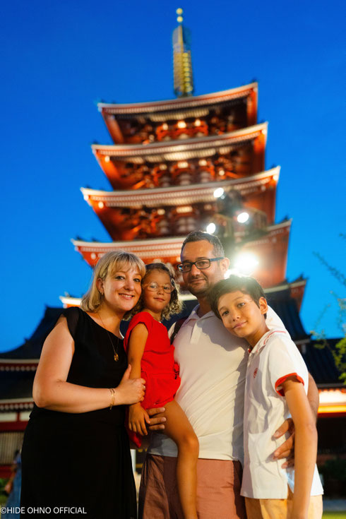 Happy family posing in front of the illuminated five-storied pagoda at Sensoji Temple during a summer evening in Asakusa, Tokyo