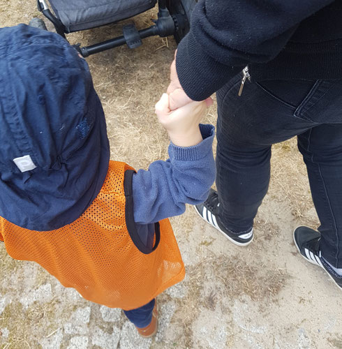 Kleinkind Hand in Hand mit Kita-Erzieherin während der Eingewöhnung.