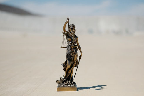 Eine kleine weibliche Skulptur mit einer Waage in der Hand als Symbol für eine neue ökologische und wirtschaftliche Gerechtigkeit globalen System.
