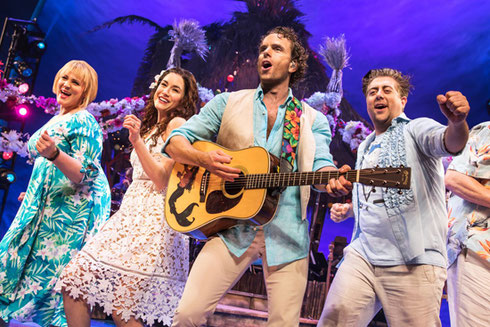 The cast of Escape to Margaritaville singing with guitars 