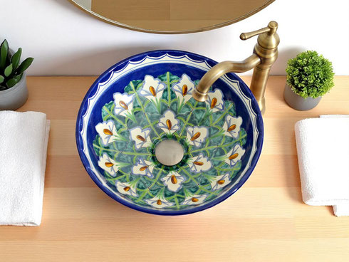 Rundes mexikanisches Keramikwaschbecken mit Calla-Blumen, auf hellemHolzwaschtisch mit goldener Armatur und Dekoration.