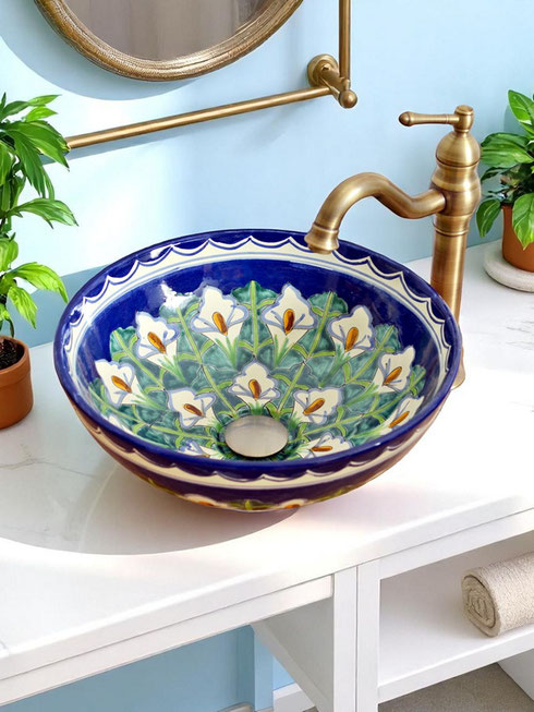 Mexikanisches Aufsatzwaschbecken mit handbemalten Calla-Blumen auf blauem Hintergrund, auf weißem Waschtisch mit Pflanzen.