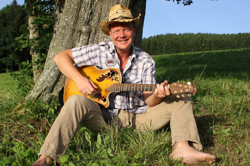 Roland Stiegler (Waldpädagoge) mit Gitarre am Baum Irrsberg