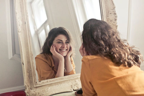 femme souriante se regarde dans un miroir thérapie de l'attachement