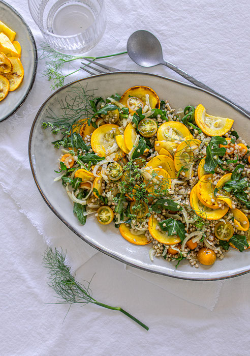 Bunter Buchweizensalat mit gebratener Zucchini, frischem Fenchel und gelben Tomaten auf einem Teller – leichter Sommersalat.